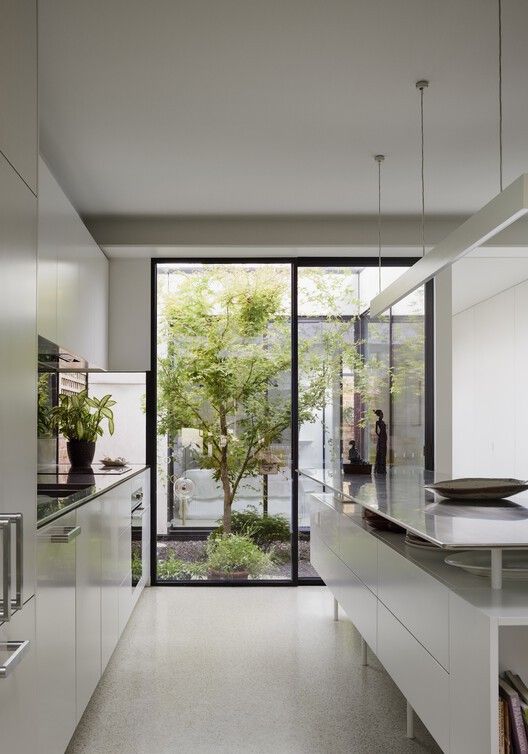 _ 6 Modern kitchen with white cabinets, large window, and view of lush garden, creating a bright and serene cooking space. | Sky Rye Design Modern kitchen with white cabinets, large window, and view of lush garden, creating a bright and serene cooking space.