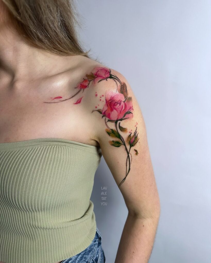 Woman with a pink rose shoulder tattoo wearing a strapless green top, displaying detailed floral design and delicate color gradients.