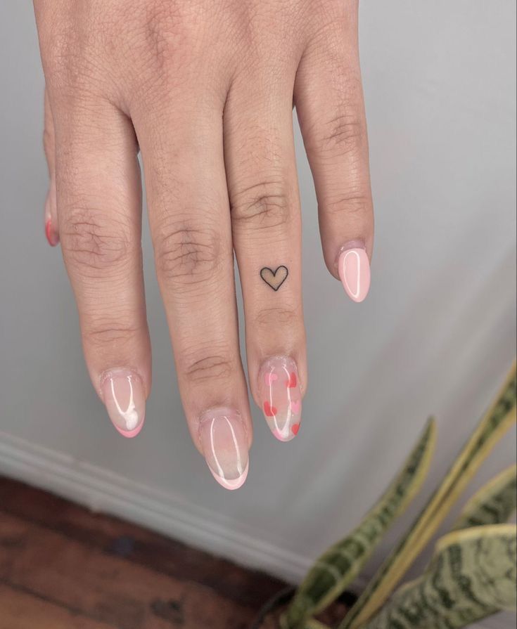 6bf4c311061b65e3745b0e7f7723f18a Hand with pink and white nail art, small heart tattoo on ring finger. Minimalist design. | Sky Rye Design Hand with pink and white nail art, small heart tattoo on ring finger. Minimalist design.