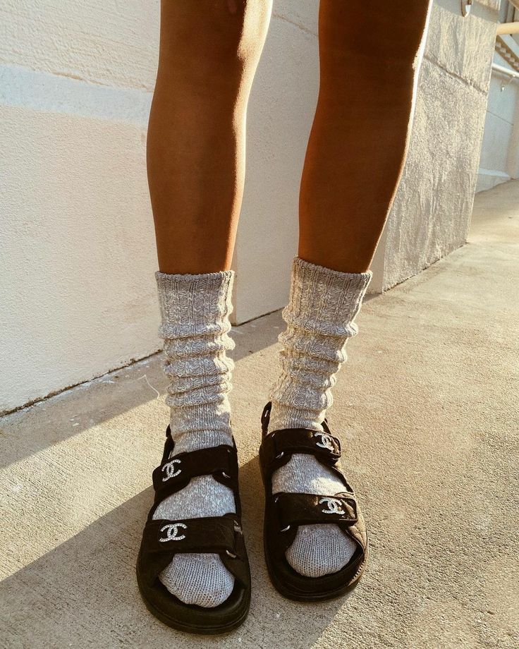 Fashion trend: Cozy grey socks paired with stylish black sandals, captured in warm sunlight on a sidewalk.