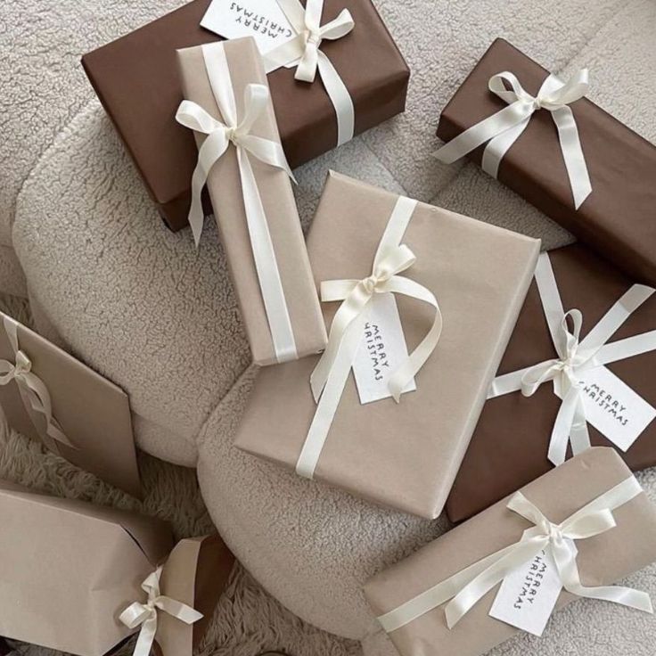 _ 7 Elegant Christmas gifts wrapped in brown and beige paper with white ribbons on a cozy background. | Sky Rye Design Elegant Christmas gifts wrapped in brown and beige paper with white ribbons on a cozy background.
