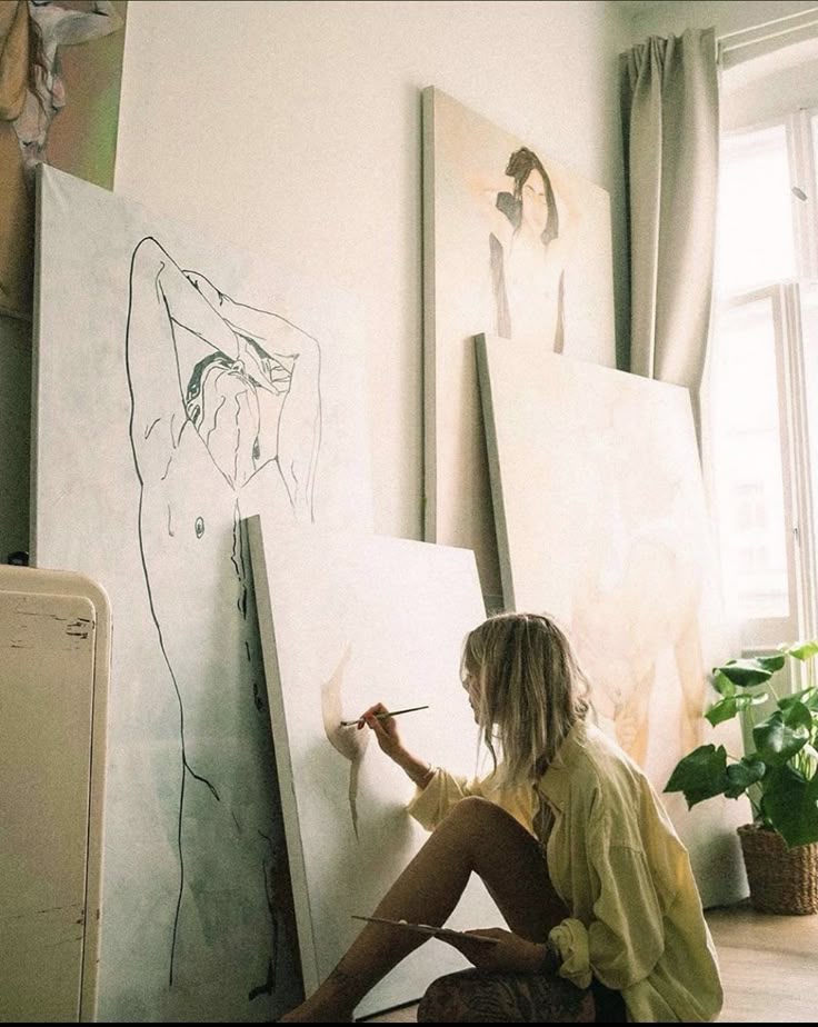 70f6ece6c7f742c41d7f0a88920959e1 Artist painting on canvas in a sunlit studio with artworks leaning against the wall. | Sky Rye Design Artist painting on canvas in a sunlit studio with artworks leaning against the wall.