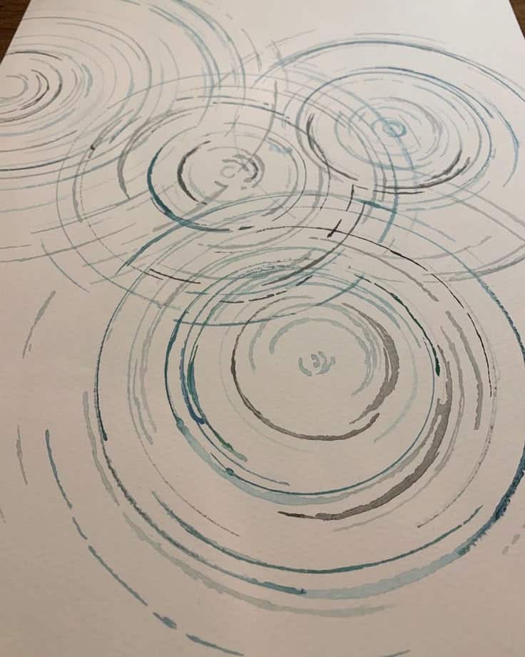 Abstract watercolor circles in blue and gray, creating a ripple effect on white paper. Minimalist and modern art design.