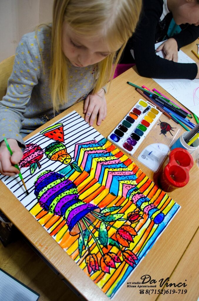 Young girl painting a colorful abstract artwork with watercolors at an art studio.