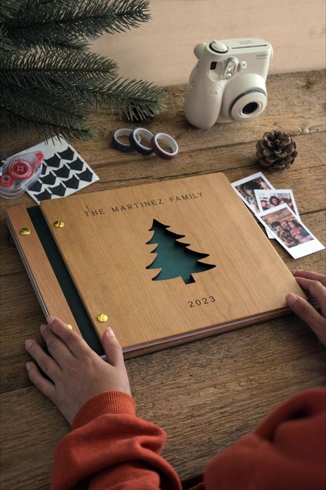 Photo album labeled The Martinez Family 2023 with a camera, pinecone, and photos on a wooden table.