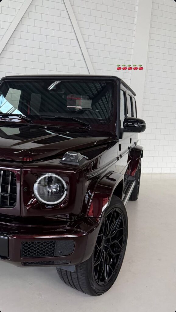 Luxury dark SUV showcasing sleek design and modern headlights in a spacious, bright showroom.