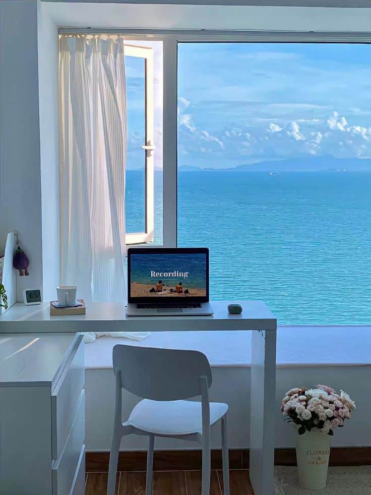 7b4c2386-af5c-4dc3-9e06-ef10b3b46840 Home office with laptop by an open window overlooking the ocean, creating a serene and inspiring workspace. | Sky Rye Design Home office with laptop by an open window overlooking the ocean, creating a serene and inspiring workspace.