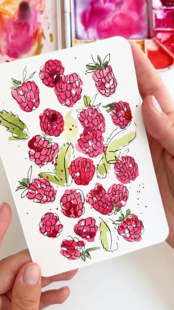 7f2c74ac-c0fc-4faf-ba3f-d8f0a930cb1c Hand-painted raspberries on a card, held by two hands, with a watercolor palette in the background. Vibrant pink and green hues. | Sky Rye Design Hand-painted raspberries on a card, held by two hands, with a watercolor palette in the background. Vibrant pink and green hues.