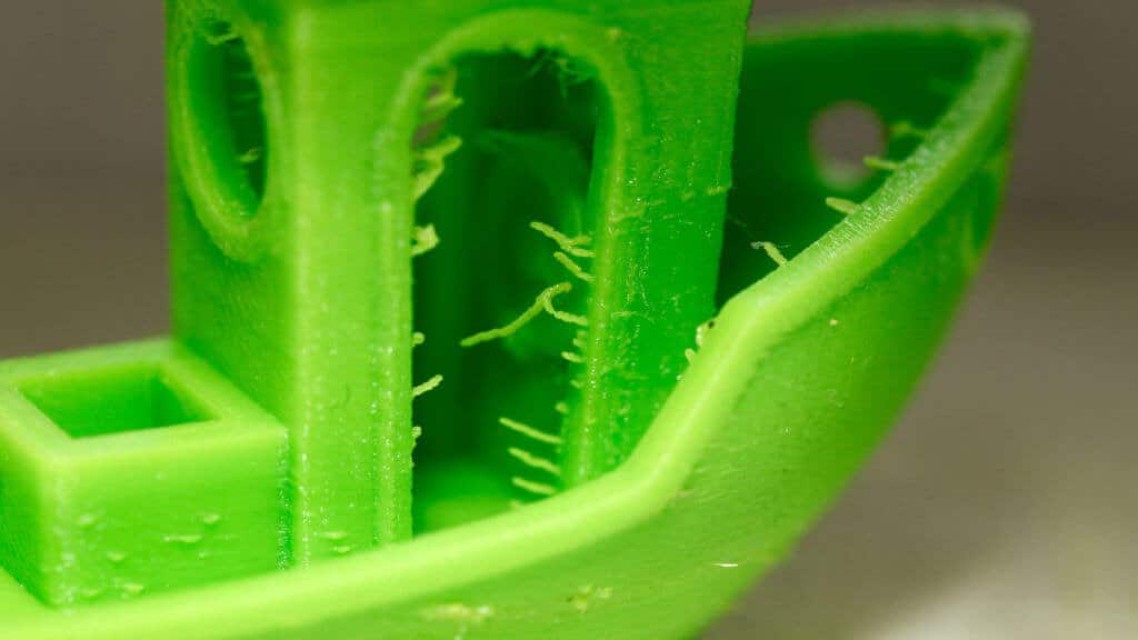 8-1 Close-up of a 3D-printed green model with visible stringing issues, commonly seen in FDM printing, showcasing filament imperfections. | Sky Rye Design Close-up of a 3D-printed green model with visible stringing issues, commonly seen in FDM printing, showcasing filament imperfections.