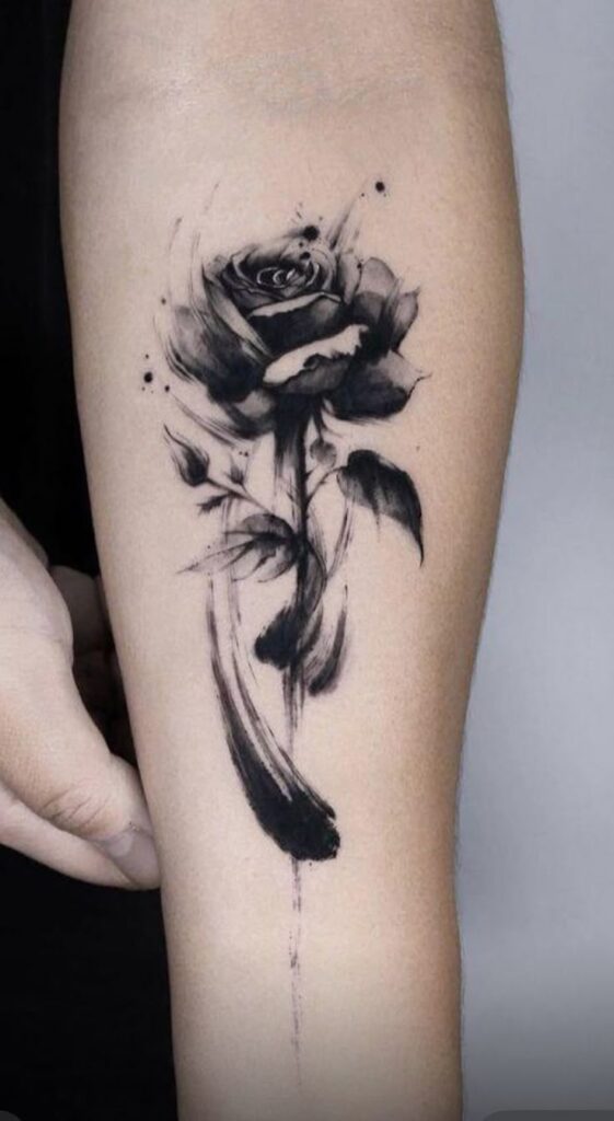 Black watercolor rose tattoo design on forearm, showcasing artistic brushstroke details and elegance in monochrome ink.
