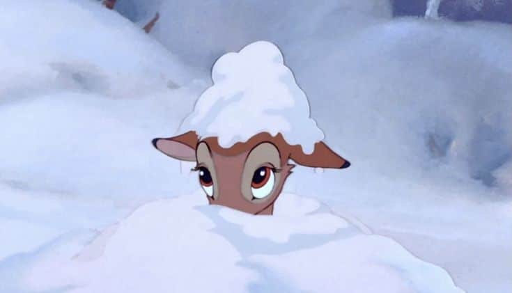 Animated deer with snow on its head peeking out from a snowy landscape, showcasing a playful and wintry scene in a forest setting.