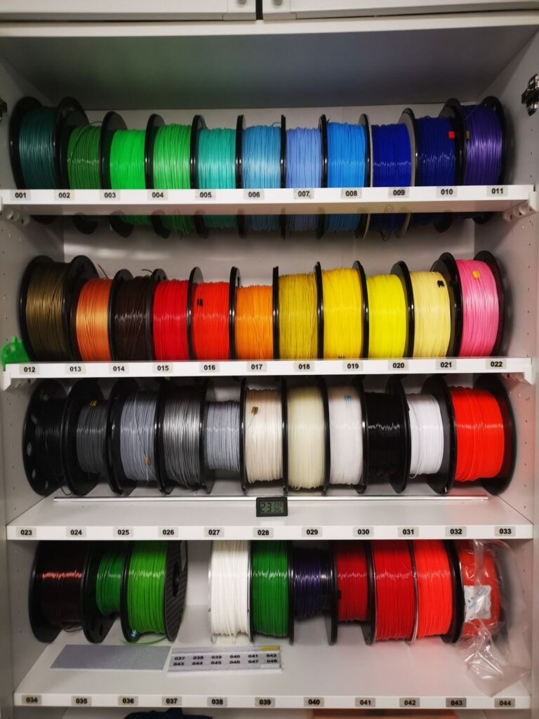 874a1ad3766e7f4d99543350591df559 Spools of colorful 3D printer filament neatly organized on shelves in a workshop. | Sky Rye Design Spools of colorful 3D printer filament neatly organized on shelves in a workshop.