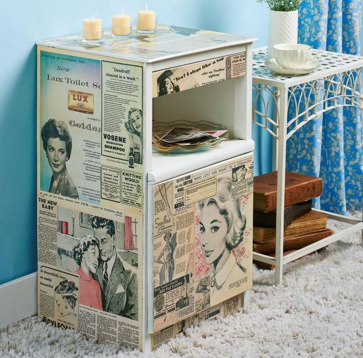 Vintage-style nightstand with retro newspaper decoupage, featuring black-and-white images and pastel accents, next to a stack of books on carpet.