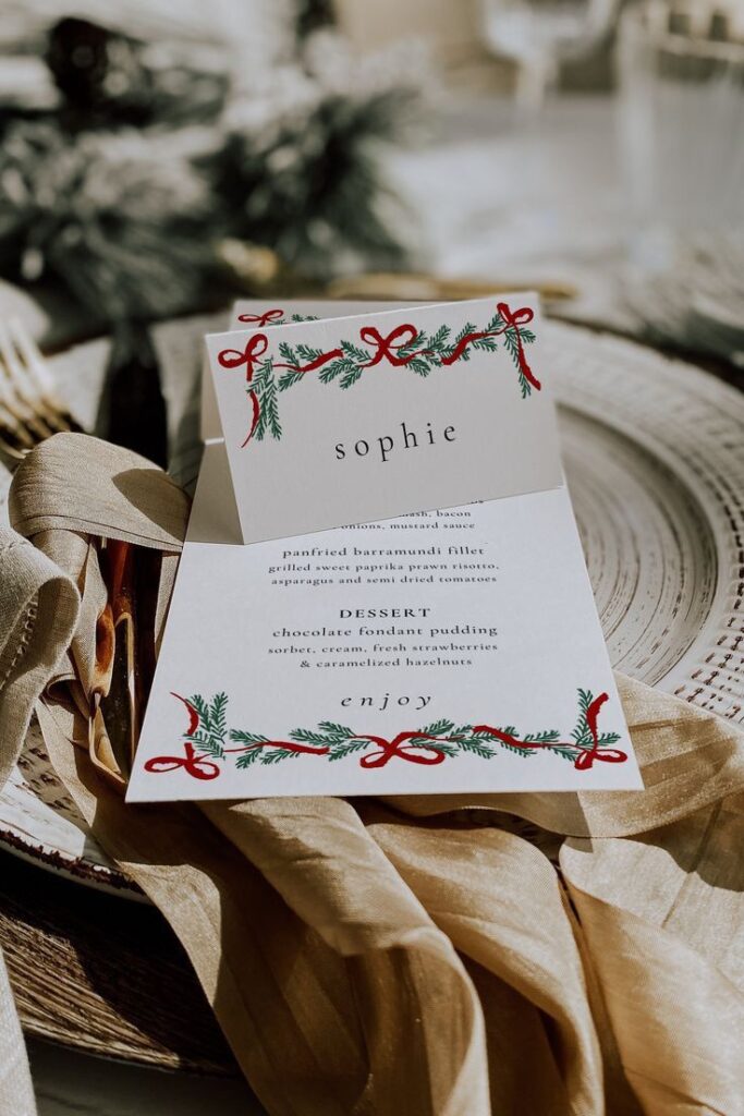 Elegant holiday menu card on a decorated table setting with festive pine and red ribbon accents, perfect for Christmas dining.