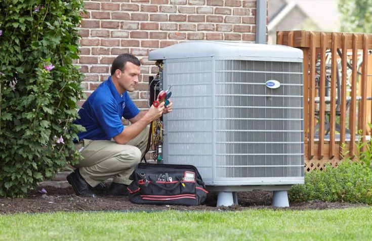 Technician repairing outdoor air conditioning unit next to brick wall, with tools in bag, ensuring efficient HVAC performance.