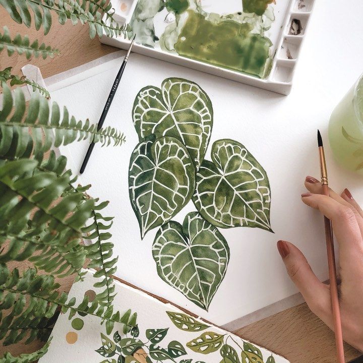 923fdffb-6a0e-422c-9669-b5214cb27d55 Person painting green leaves with watercolor, surrounded by art supplies and plants, focusing on botanical art creativity. | Sky Rye Design Person painting green leaves with watercolor, surrounded by art supplies and plants, focusing on botanical art creativity.