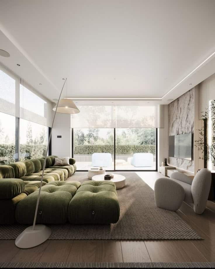 A cozy living room with a woven pouf and neutral tones provides a relaxing atmosphere_ Modern living room with green sectional sofa, stylish chairs, large windows, and natural light. | Sky Rye Design Modern living room with green sectional sofa, stylish chairs, large windows, and natural light.