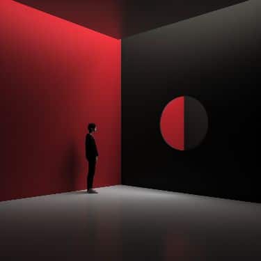 Person stands in a dimly lit room with red and black walls, gazing at a circular art piece. Minimalistic and modern design.