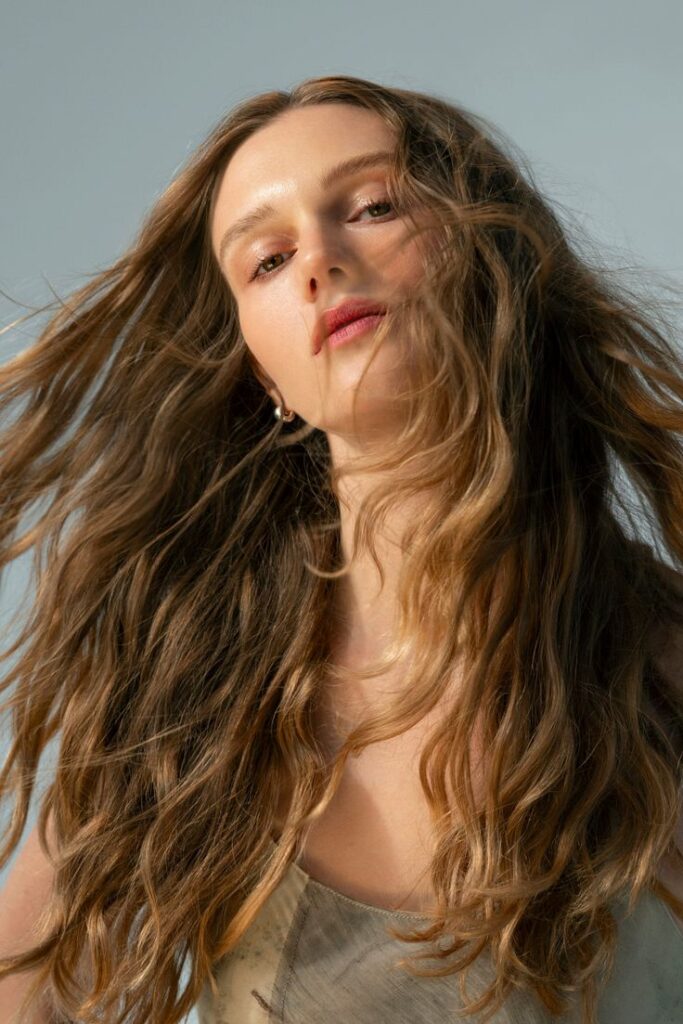 Air Thickening Spray Young woman with long flowing hair and natural makeup, looking confidently at the camera against a light background. | Sky Rye Design Young woman with long flowing hair and natural makeup, looking confidently at the camera against a light background.