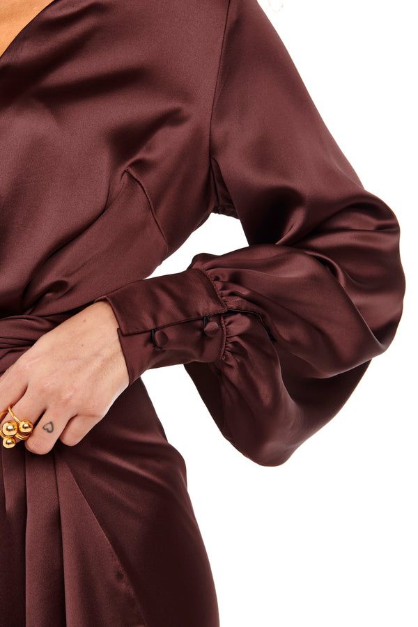 All Womens Clothing Elegant maroon satin dress with puff sleeves and buttoned cuffs, featuring a stylish gold ring on a woman's hand. Perfect for evening wear. | Sky Rye Design Elegant maroon satin dress with puff sleeves and buttoned cuffs, featuring a stylish gold ring on a woman's hand. Perfect for evening wear.