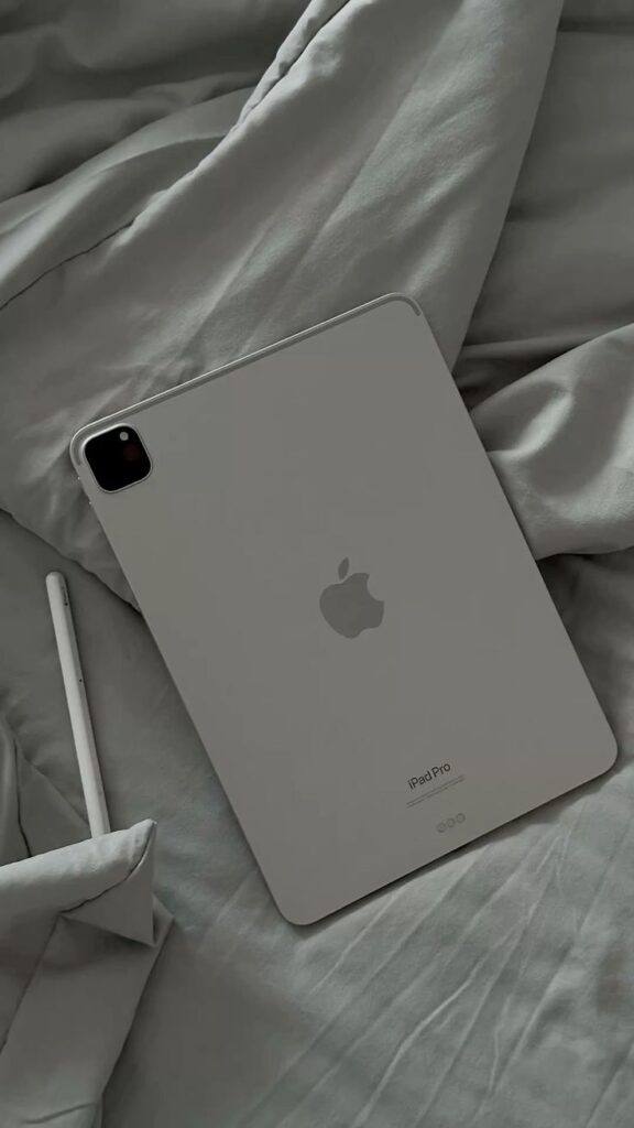Apple 🍏 Gray iPad Pro with Apple Pencil on soft bed sheets, showcasing sleek design and modern technology. | Sky Rye Design Gray iPad Pro with Apple Pencil on soft bed sheets, showcasing sleek design and modern technology.