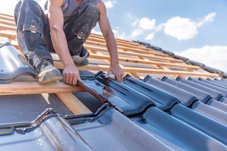 Applications Archives - Page 12 of 17 - Urban_ Worker installing black roof tiles on wooden structure under blue sky. | Sky Rye Design Worker installing black roof tiles on wooden structure under blue sky.