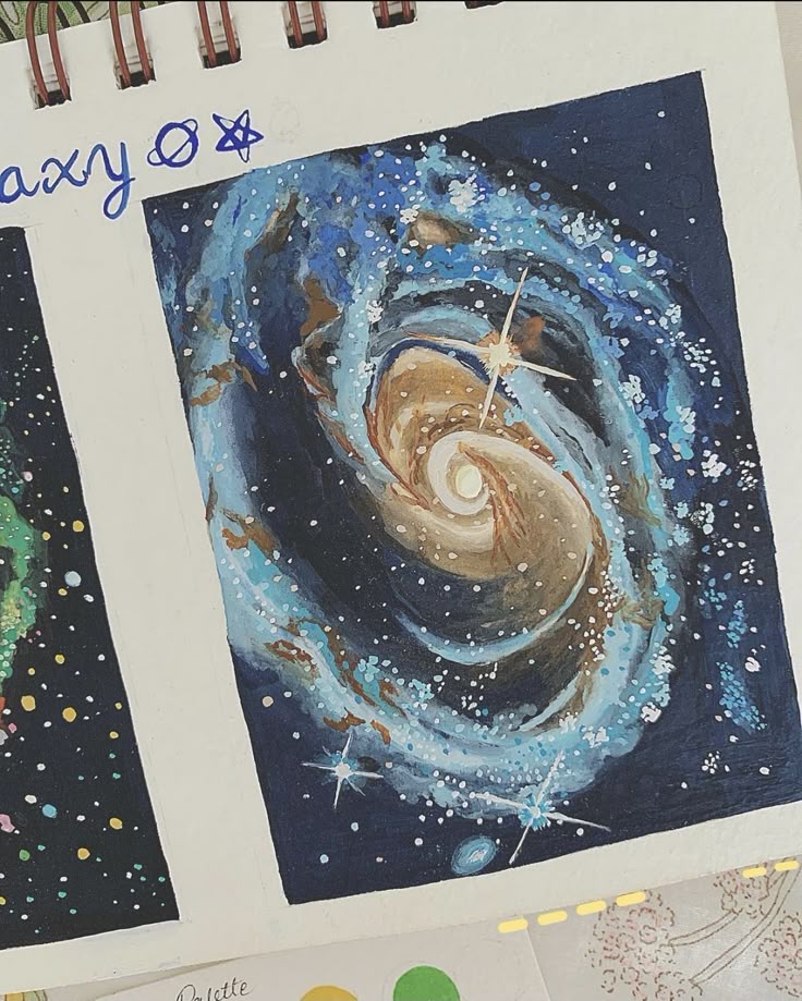Colorful galaxy spiral painting in a sketchbook, showcasing vibrant cosmic swirls of blue, brown, and white with starry details.