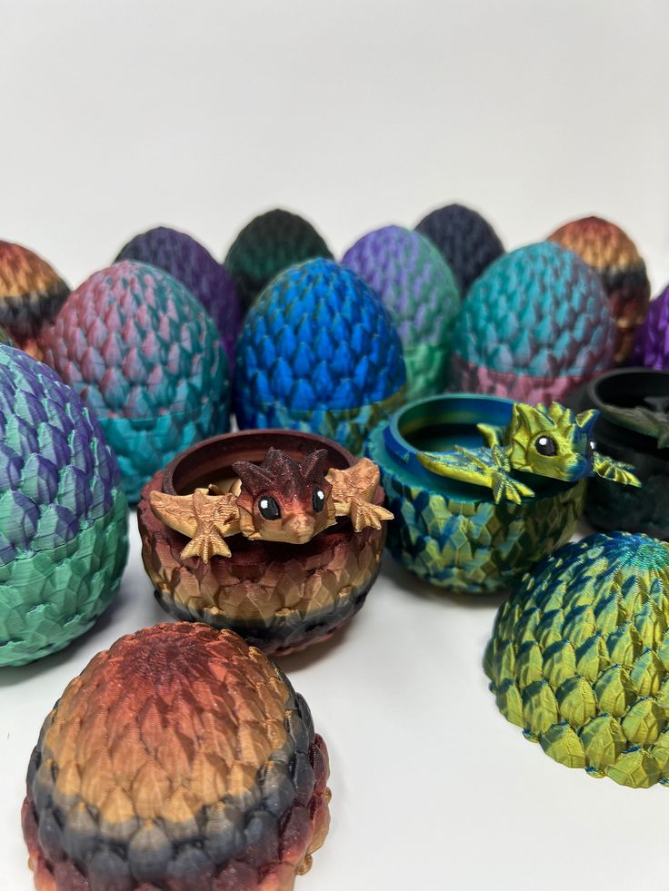 Colorful dragon eggs with small dragons hatching, featuring scales in vibrant hues of blue, green, and red on a white background.