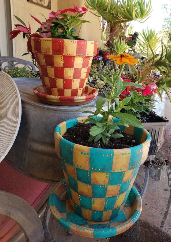 Colorful checkered pots with vibrant flowers on a sunny patio setting, showcasing creative garden decor and plant arrangement.