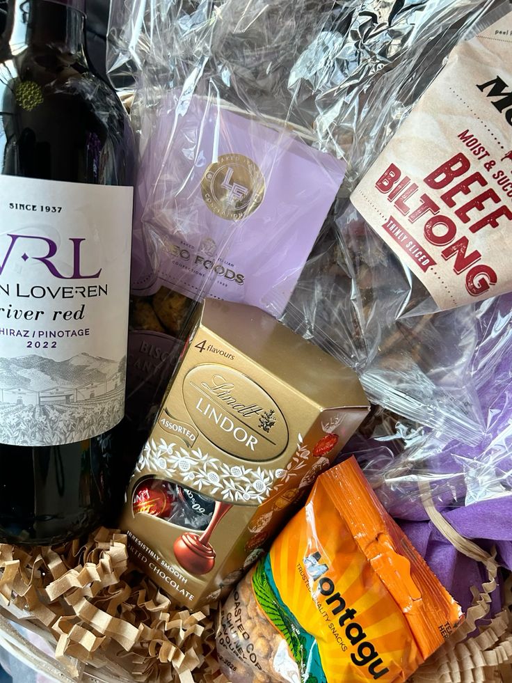 Birthday hamper Gift basket with red wine, Lindt chocolates, beef biltong, and assorted snacks, wrapped in cellophane. Perfect for celebrations. | Sky Rye Design Gift basket with red wine, Lindt chocolates, beef biltong, and assorted snacks, wrapped in cellophane. Perfect for celebrations.