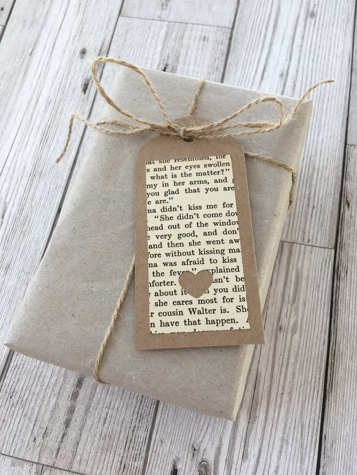 Book Page Gift Tags Heart or Snowflake gift tags Gift wrapped in brown paper with twine and a vintage book page tag featuring a heart cutout, placed on a wooden surface. | Sky Rye Design Gift wrapped in brown paper with twine and a vintage book page tag featuring a heart cutout, placed on a wooden surface.