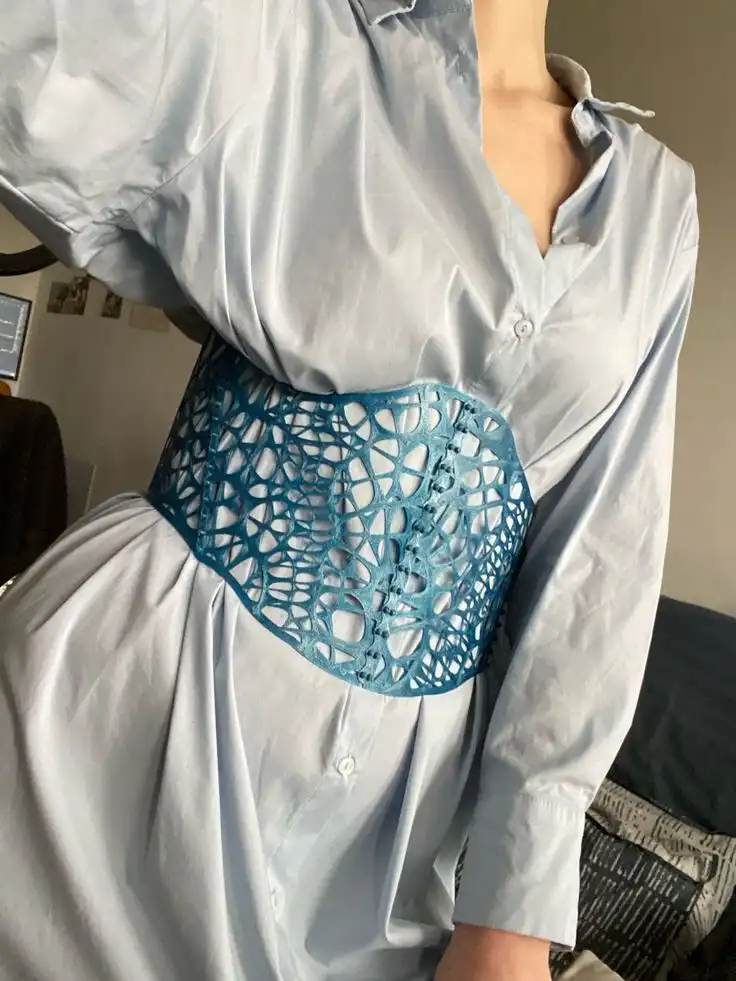 Woman wearing a light blue shirt dress with a stylish blue lace belt, showcasing modern fashion and unique accessory styling.