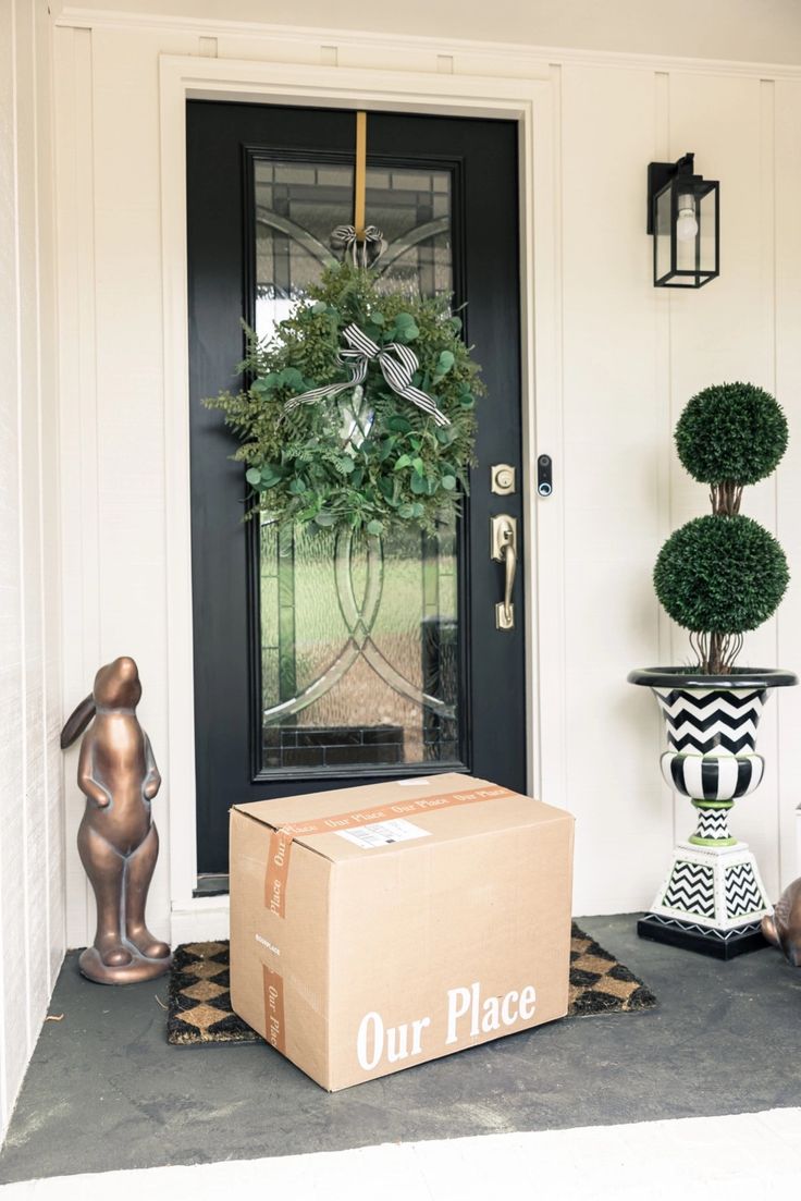 Celebrate Thanksgiving At Our Place Cardboard box from Our Place on a doorstep with wreath on black door, flanked by a topiary and bronze rabbit decoration. | Sky Rye Design Cardboard box from Our Place on a doorstep with wreath on black door, flanked by a topiary and bronze rabbit decoration.
