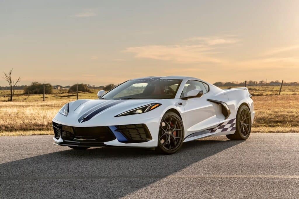 Sleek white sports car with racing stripes parked on a rural road at sunset, showcasing its modern design and aerodynamic features.
