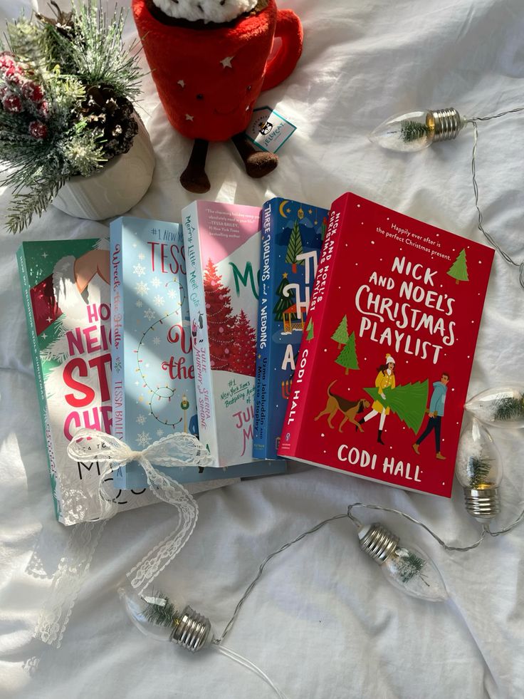 Festive book collection with a Christmas theme, featuring novels and decorations on a white surface with string lights.