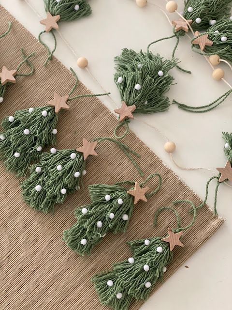 Handcrafted festive garland featuring green yarn Christmas trees with wooden stars and white beads on a natural fiber backdrop.