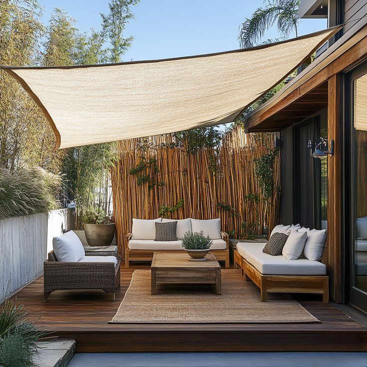 Create an Aesthetically Inviting Outdoor Living Space with These Backyard Remodel Projects Modern outdoor patio with wooden furniture, shade sail, and bamboo privacy screen, creating a cozy and stylish relaxation space in daylight. | Sky Rye Design Modern outdoor patio with wooden furniture, shade sail, and bamboo privacy screen, creating a cozy and stylish relaxation space in daylight.