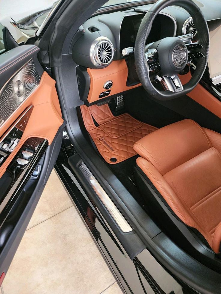 Luxury car interior with tan leather seats and sleek dashboard design. Modern steering wheel and metallic accents.