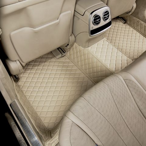 Luxury car interior with beige quilted floor mats and perforated leather seats, showcasing elegant design and comfort.