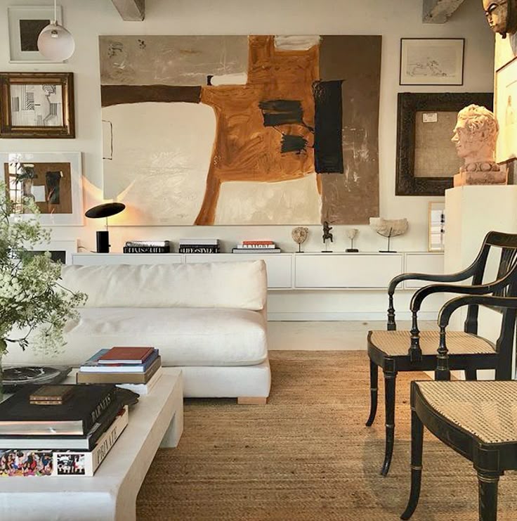 Design by William McClure Modern living room with abstract art, white sofa, black chairs, and square coffee table decorated with books. | Sky Rye Design Modern living room with abstract art, white sofa, black chairs, and square coffee table decorated with books.