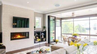 Stylish modern living room with a cozy fireplace, large windows, and plush seating, plus a serene outdoor view. Perfect blend of comfort and elegance.