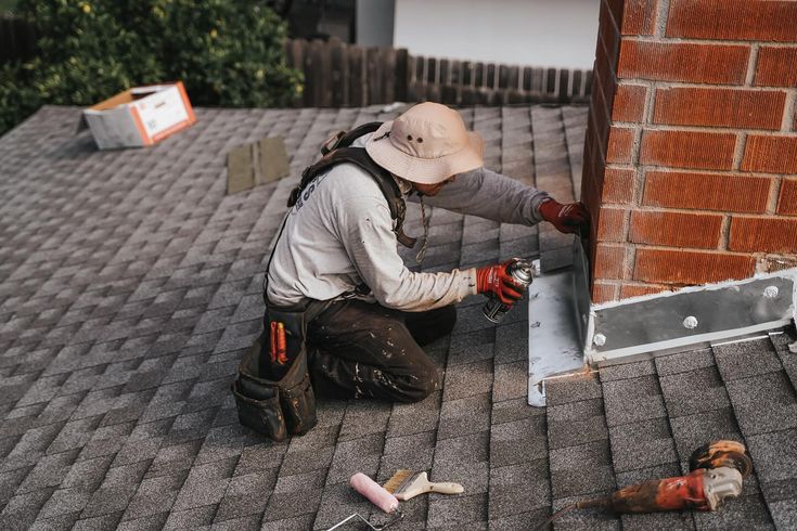 Details make the difference Trust us to elevate your roof with precision and care every single time 👏🏽👏🏽👏🏽__boycesroofing Roofer sealing chimney base on shingled roof, ensuring waterproofing and durability during home maintenance. | Sky Rye Design Roofer sealing chimney base on shingled roof, ensuring waterproofing and durability during home maintenance.