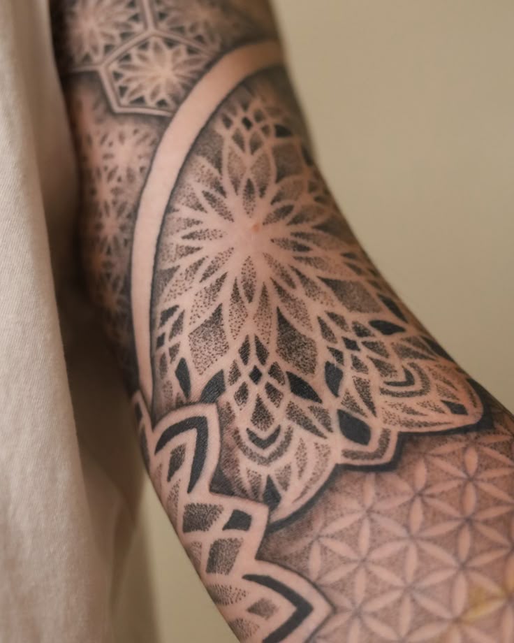 Intricate geometric tattoo sleeve with floral patterns on an arm, showcasing detailed dot work design.