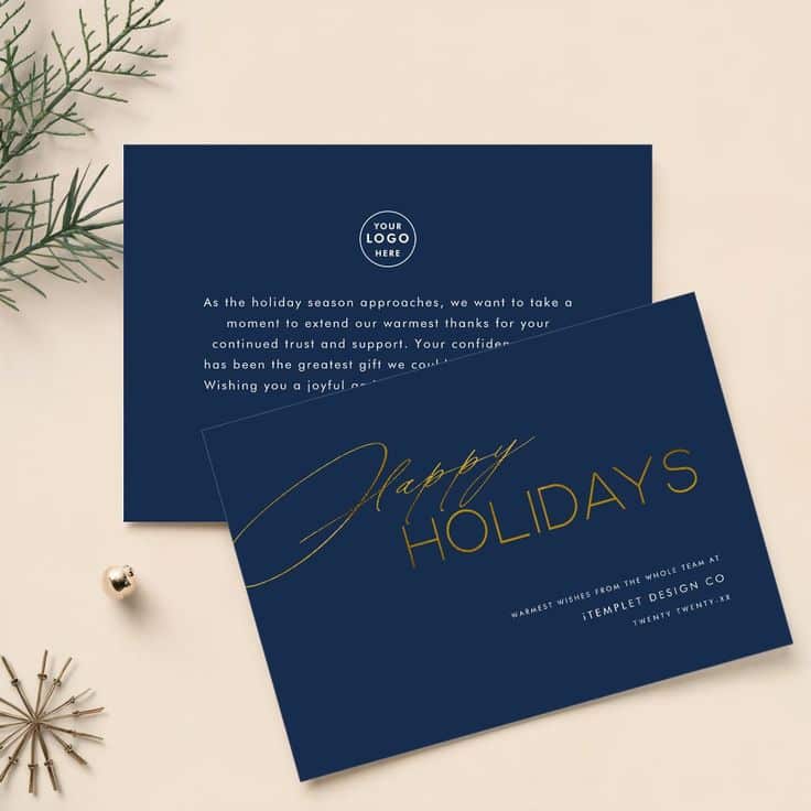 Elegant holiday card design with navy blue background, gold Happy Holidays text, and festive decorations on a beige surface.