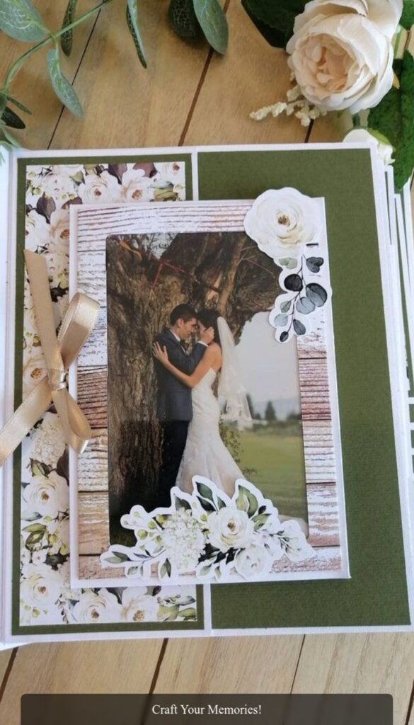 Elegant wedding scrapbook page featuring a romantic photo of a bride and groom embraced under a tree, adorned with floral embellishments.