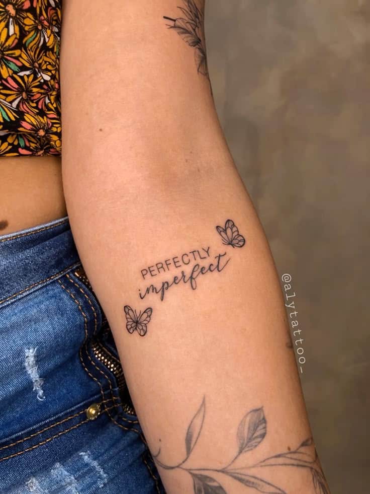 Escrita tattoo 🤍 Arm tattoo with Perfectly Imperfect text and butterflies, showcasing personal expression with floral and denim accents. | Sky Rye Design Arm tattoo with Perfectly Imperfect text and butterflies, showcasing personal expression with floral and denim accents.