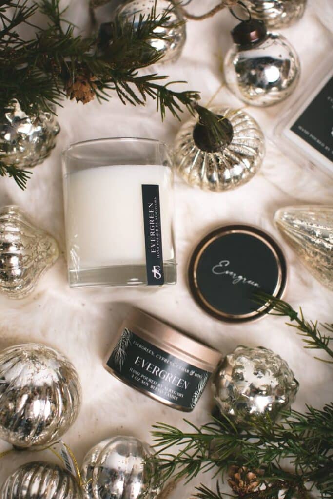 Evergreen Wooden Wick Candle Festive evergreen scented candles surrounded by silver holiday ornaments and pine branches, creating a cozy winter vibe. | Sky Rye Design Festive evergreen scented candles surrounded by silver holiday ornaments and pine branches, creating a cozy winter vibe.