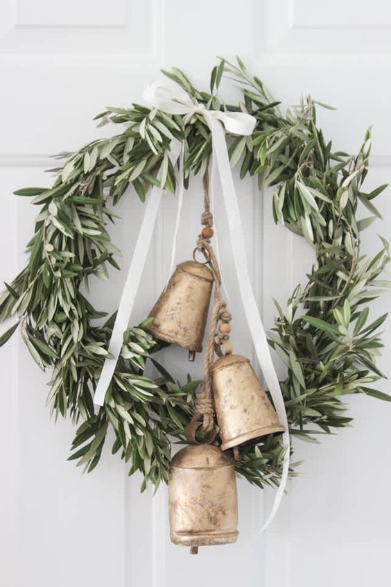 Find these bells Elegant olive wreath with golden bells and white ribbons on a light door, creating a festive, welcoming decoration. | Sky Rye Design Elegant olive wreath with golden bells and white ribbons on a light door, creating a festive, welcoming decoration.