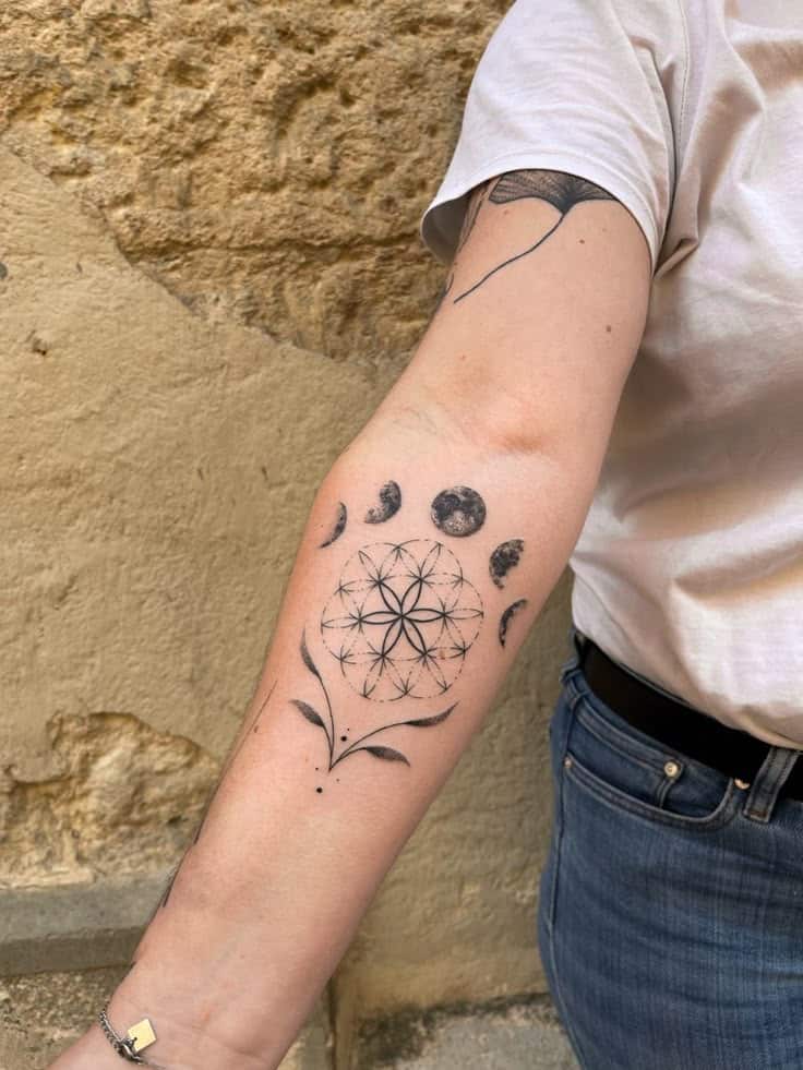 Geometric floral tattoo on forearm with moon phases, black ink on light skin, close-up shot.