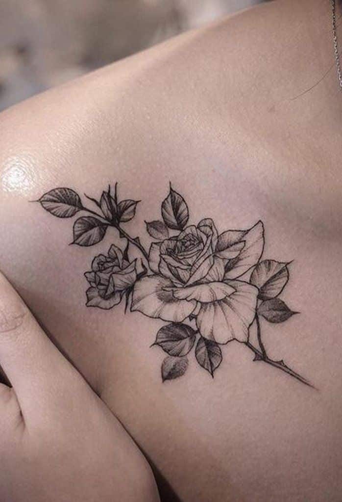 Detailed black rose tattoo on shoulder with leaves, showcasing intricate linework and artistry. Perfect for floral tattoo inspiration.